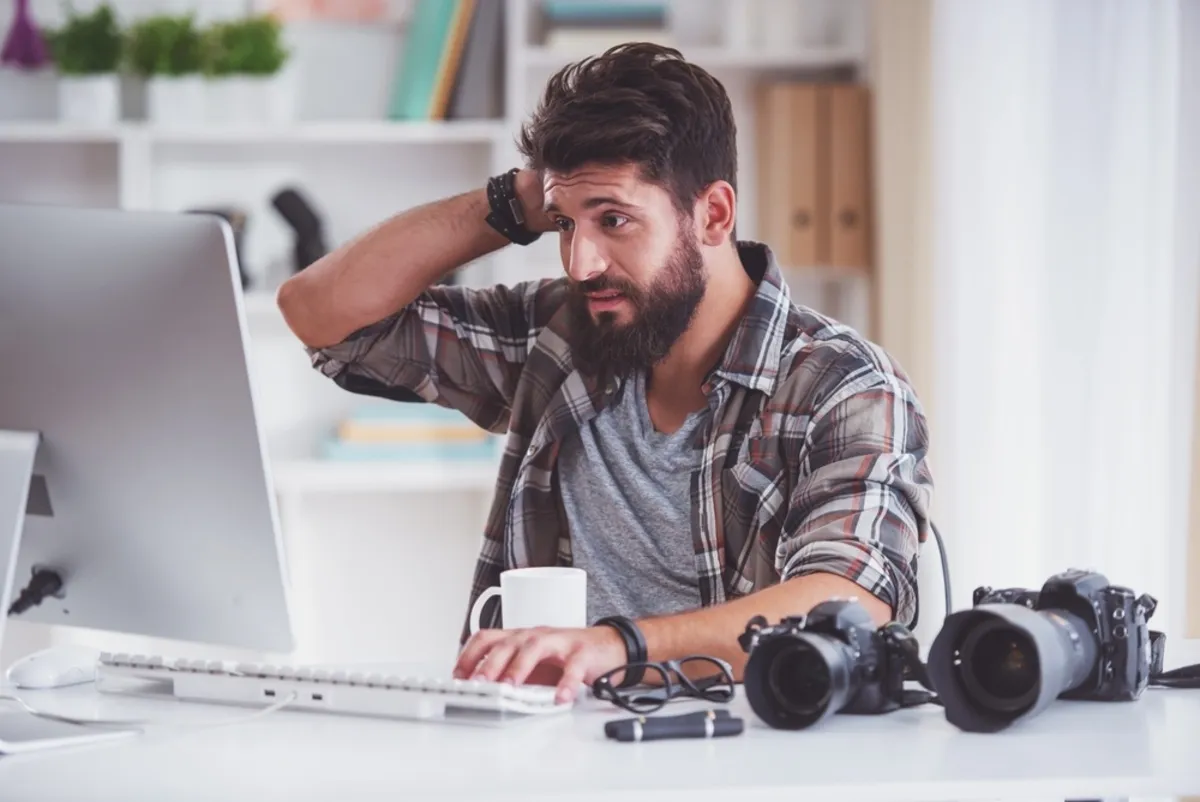 A photographer thinks at his laptop | Skylum Blog