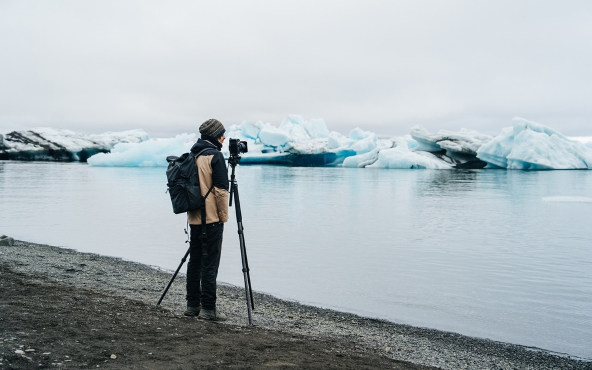 A photographer with a camera on a spit near glaciers | Skylum Blog

