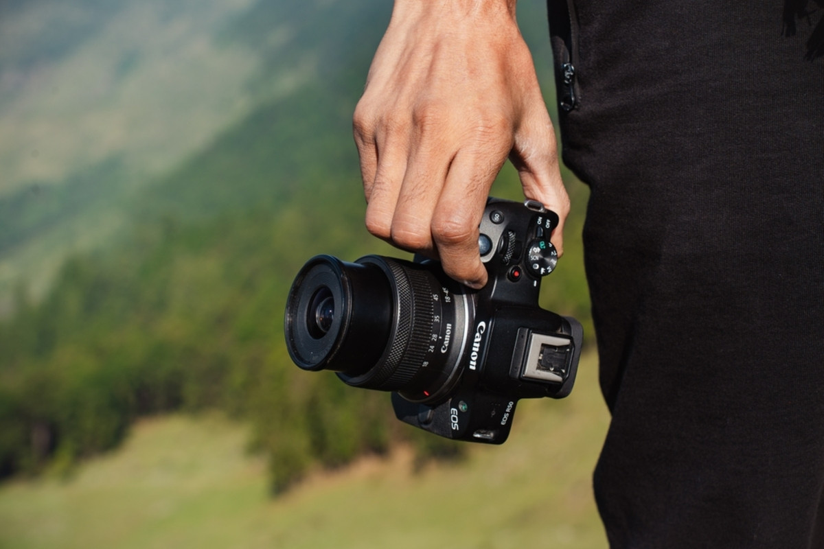 Seorang fotografer memegang Canon EOS R50 | Skylum Blog

