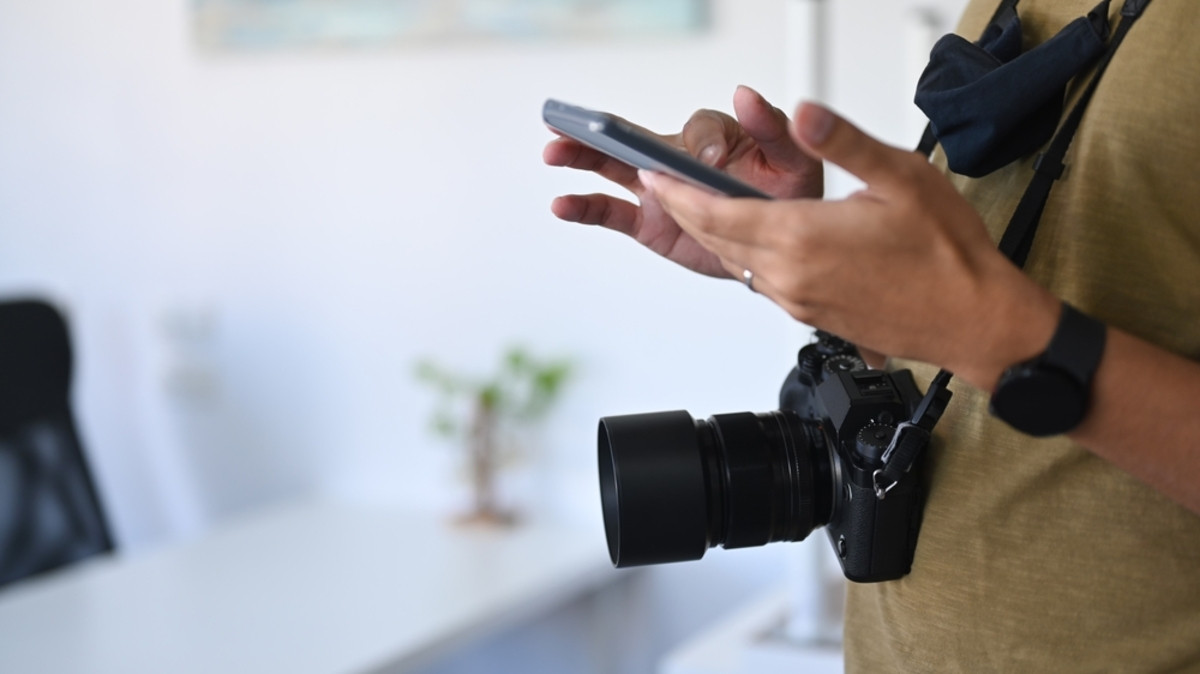 The photographer selects something on his phone | Skylum Blog