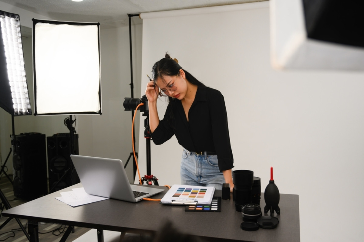 A photographer thinks while looking at a laptop in a photo studio | Skylum Blog

