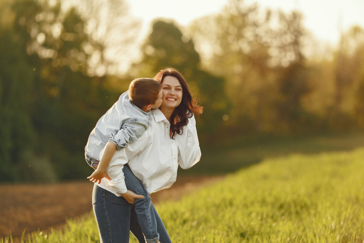 Mutter hält Sohn in einem sonnenbeschienenen Feld | Skylum Blog

