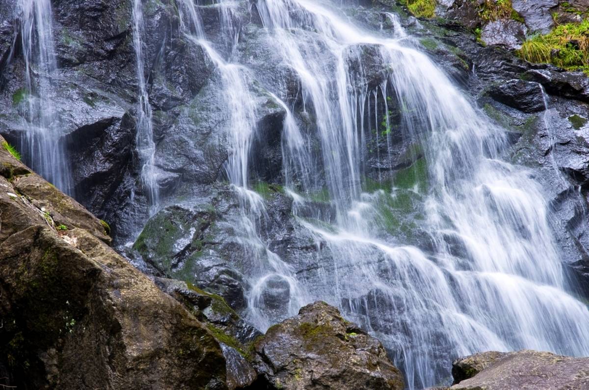 Water cascading over mossy dark rocks in a forest | Skylum Blog

