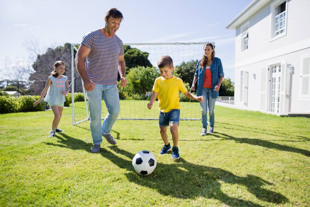 A family plays football in the yard in the summer | Skylum Blog

