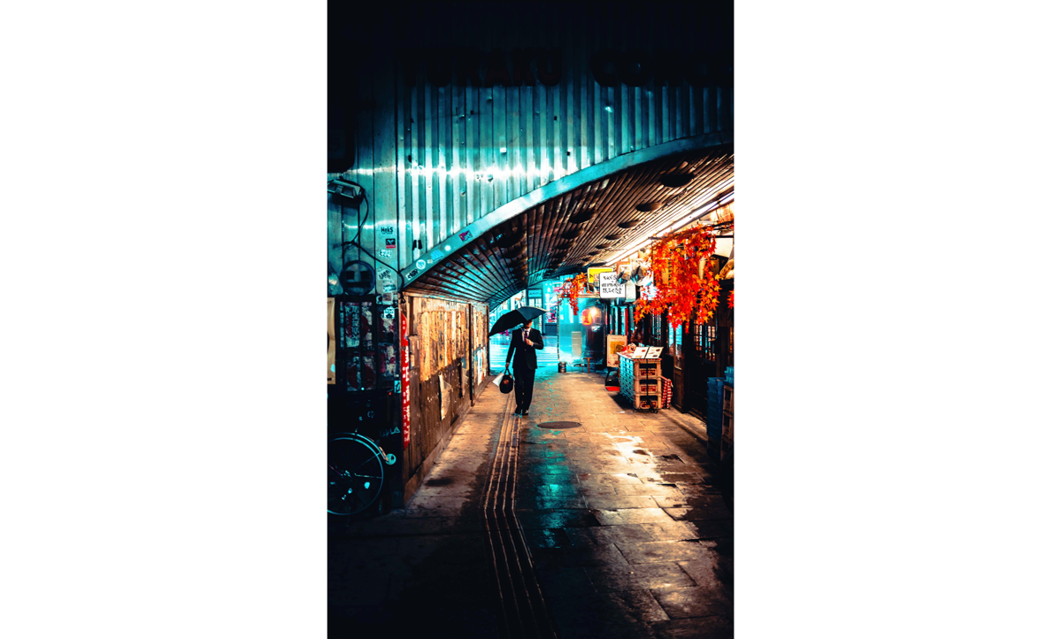 A man walks under an umbrella in the city | Skylum Blog

