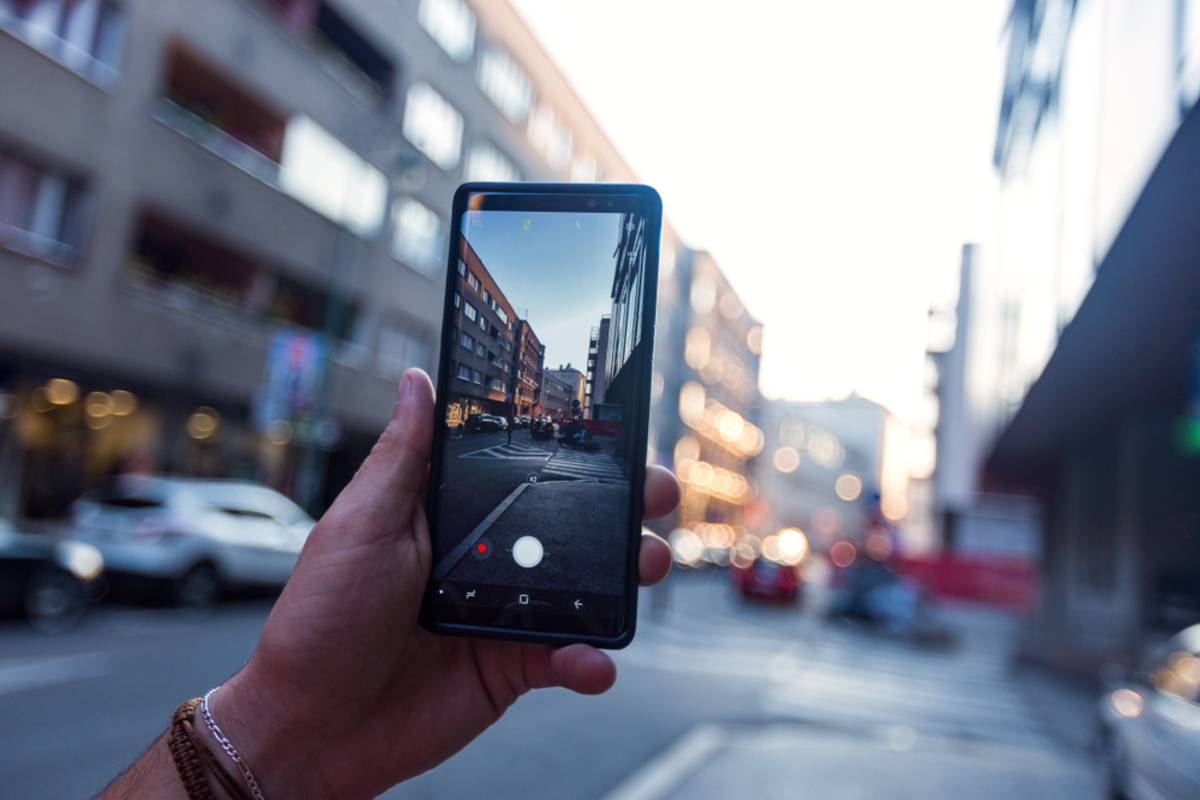 Člověk fotografující městskou ulici pomocí smartphonu | Blog Skylum

