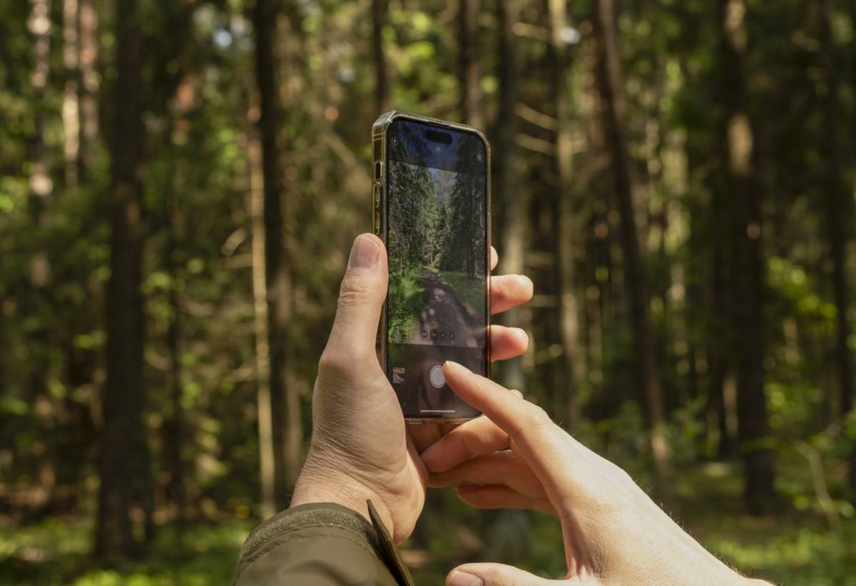 A man takes a photo of a path on his iPhone | Skylum Blog

