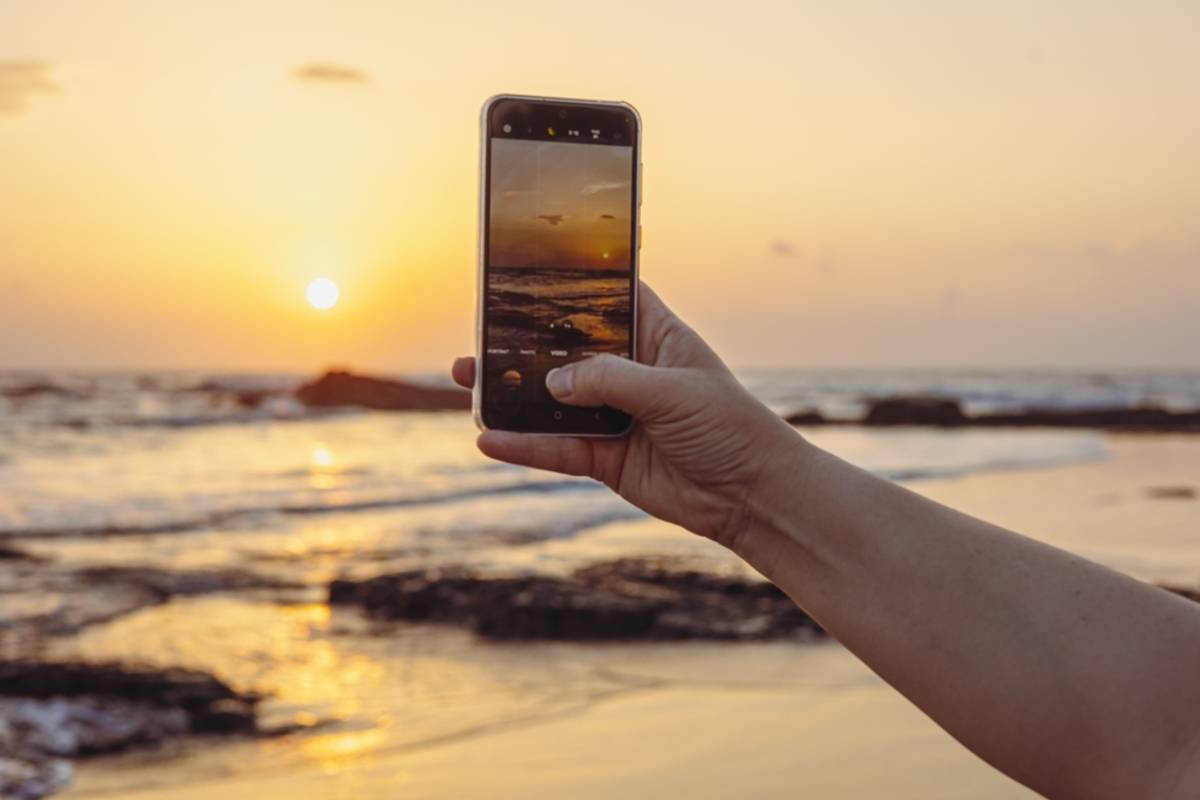 Smartphone zachycující západ slunce nad oceánem | Blog Skylum

