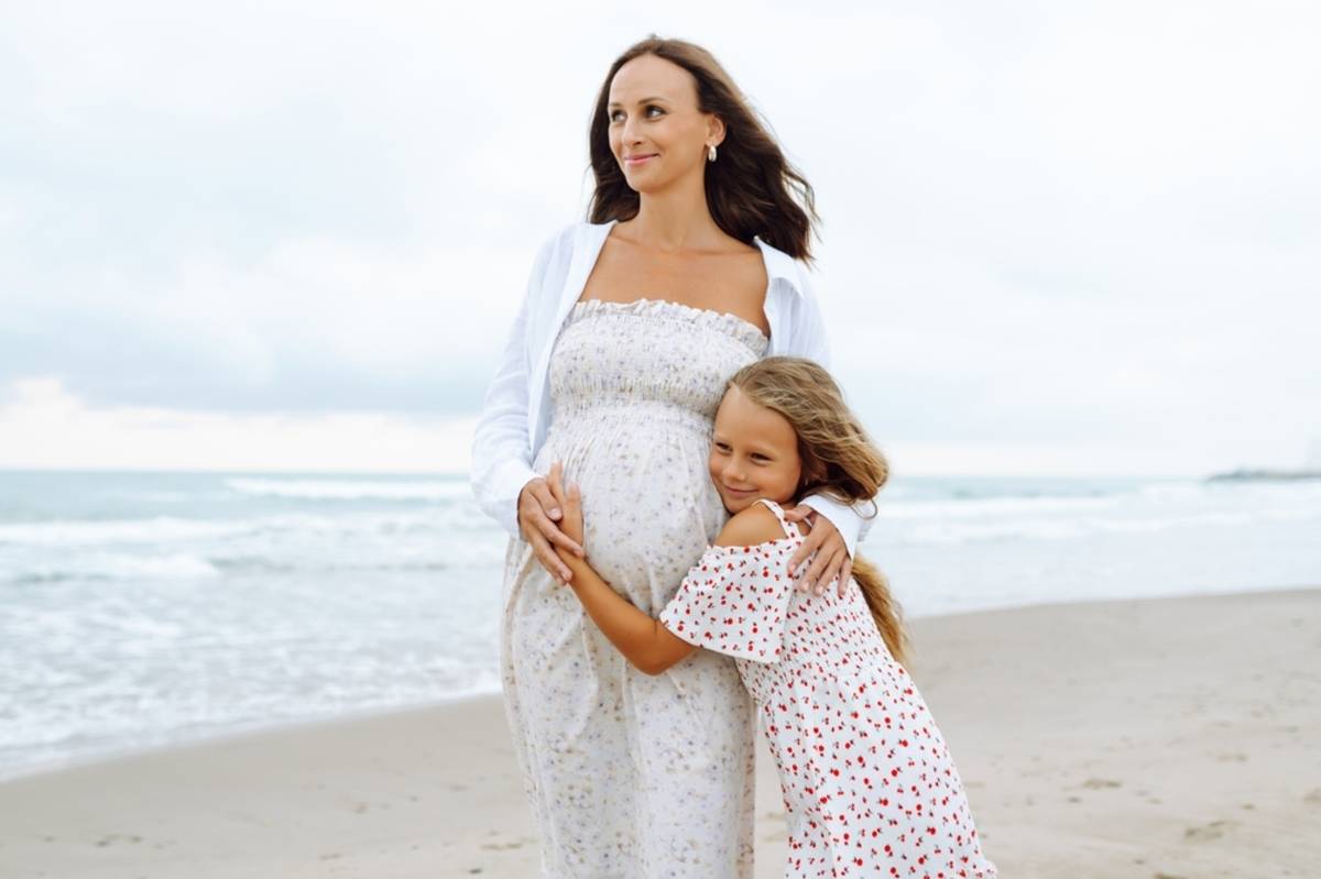Pregnant woman with young girl walking on the beach | Skylum Blog

