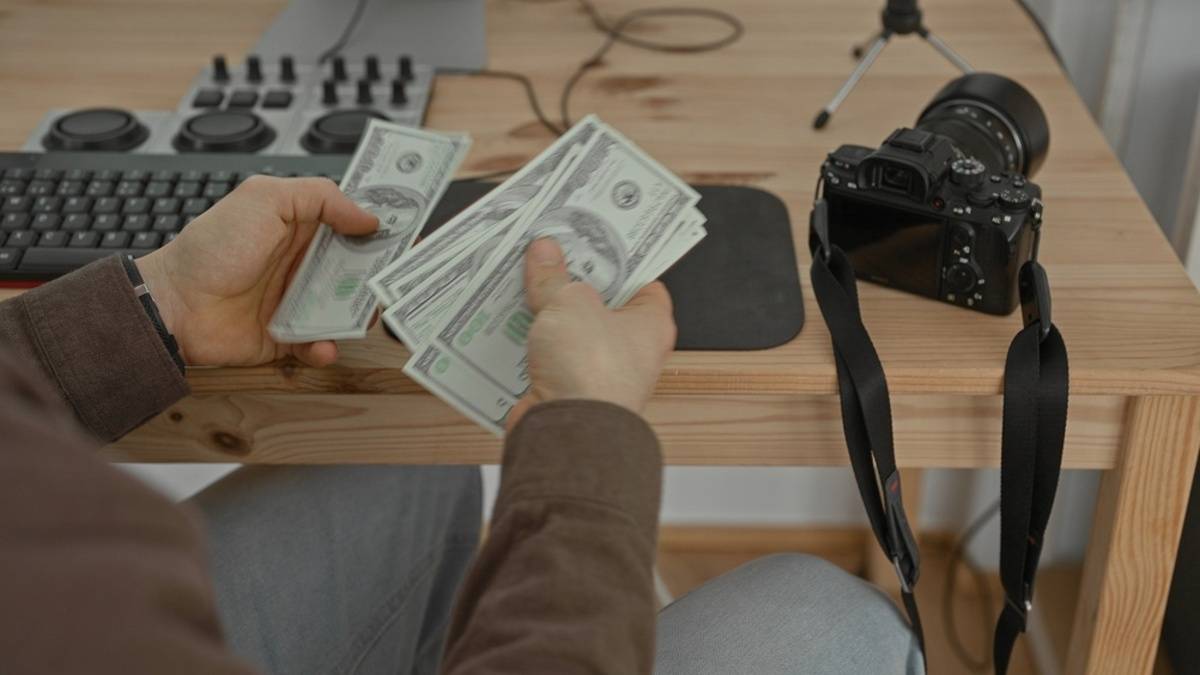 Hände, die neben einer Kamera auf einem Tisch Bargeld zählen | Skylum-Blog