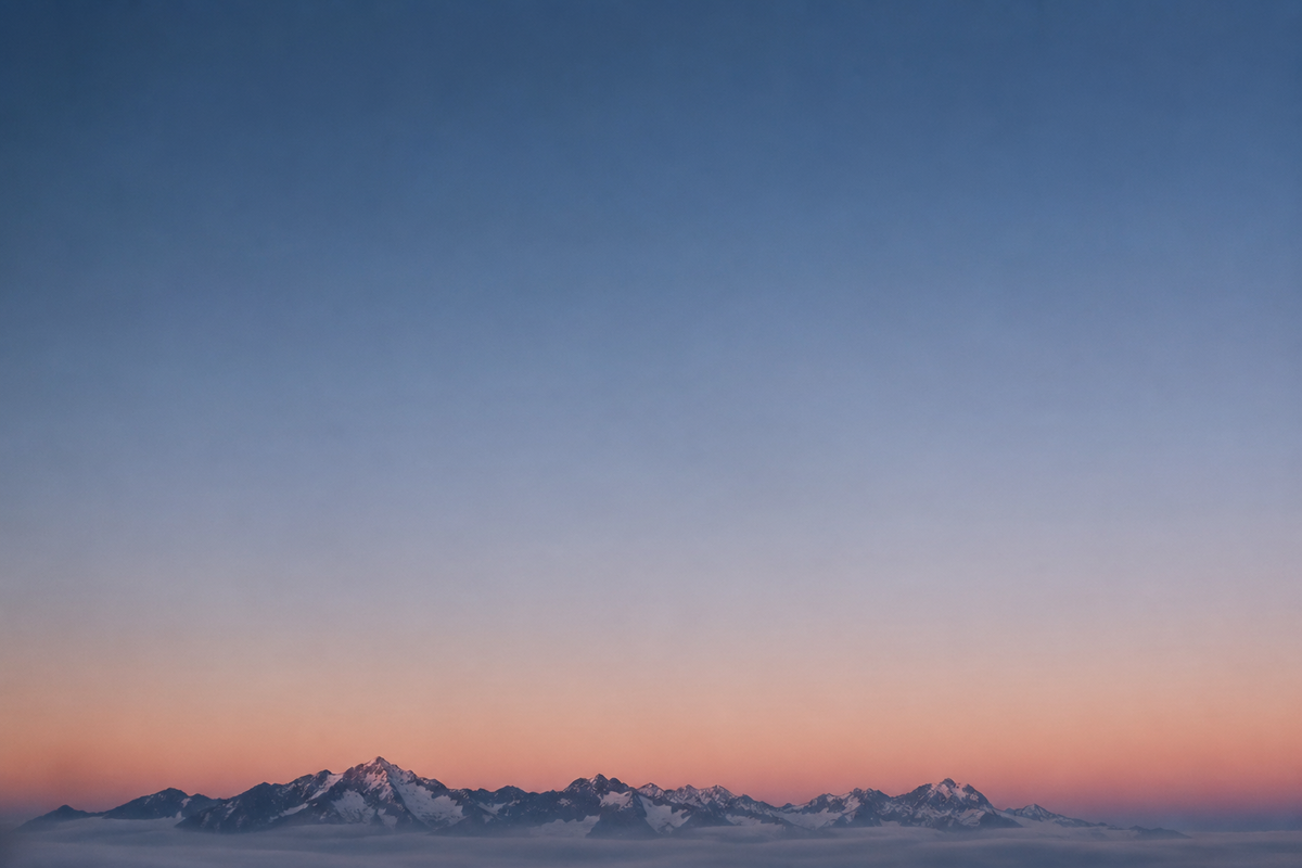 遠くの山々の地平線に沈む、シンプルで美しい夕日 | Skylumブログ   