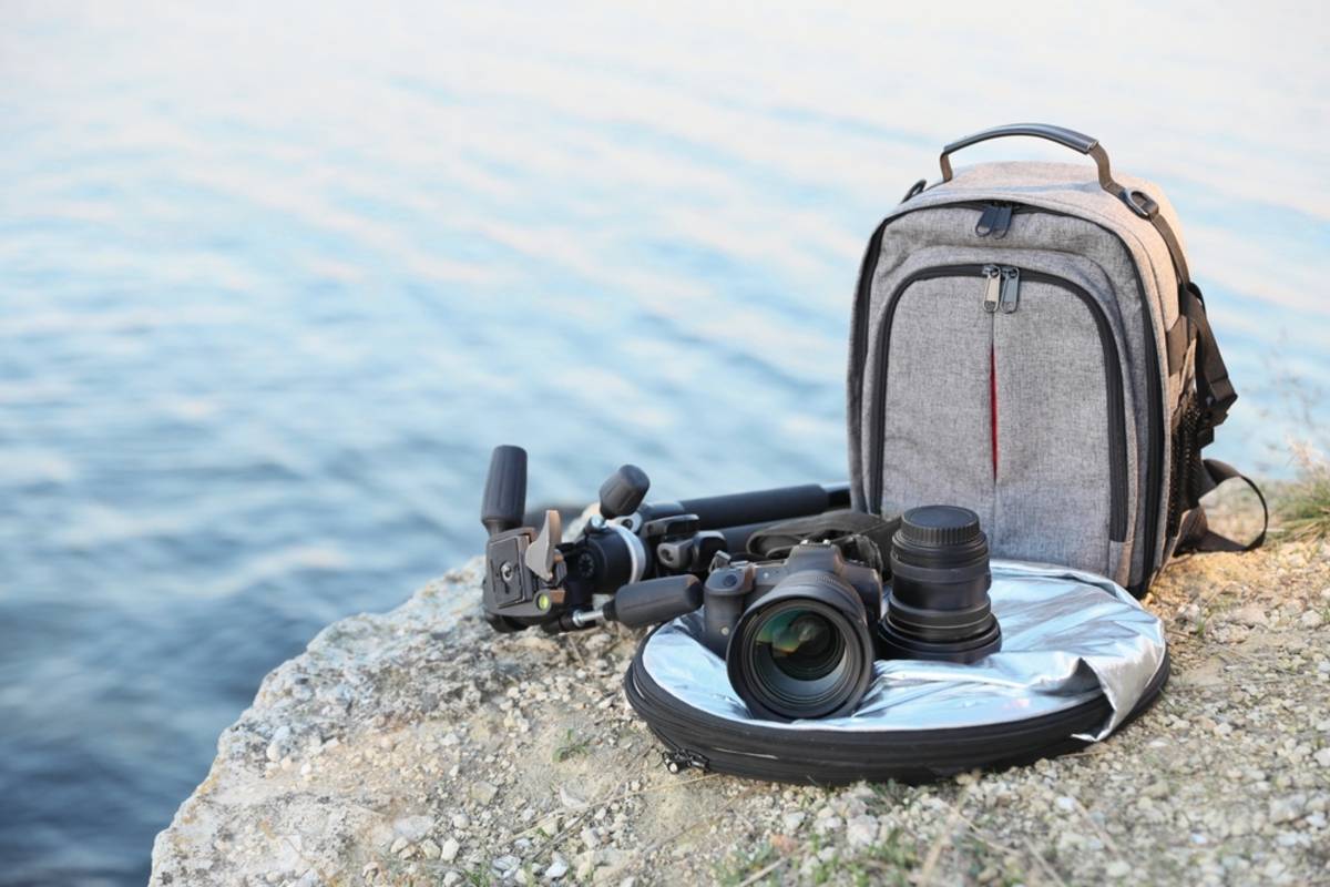 Rucksack, Kamera, Stativ am Flussufer | Skylum-Blog

