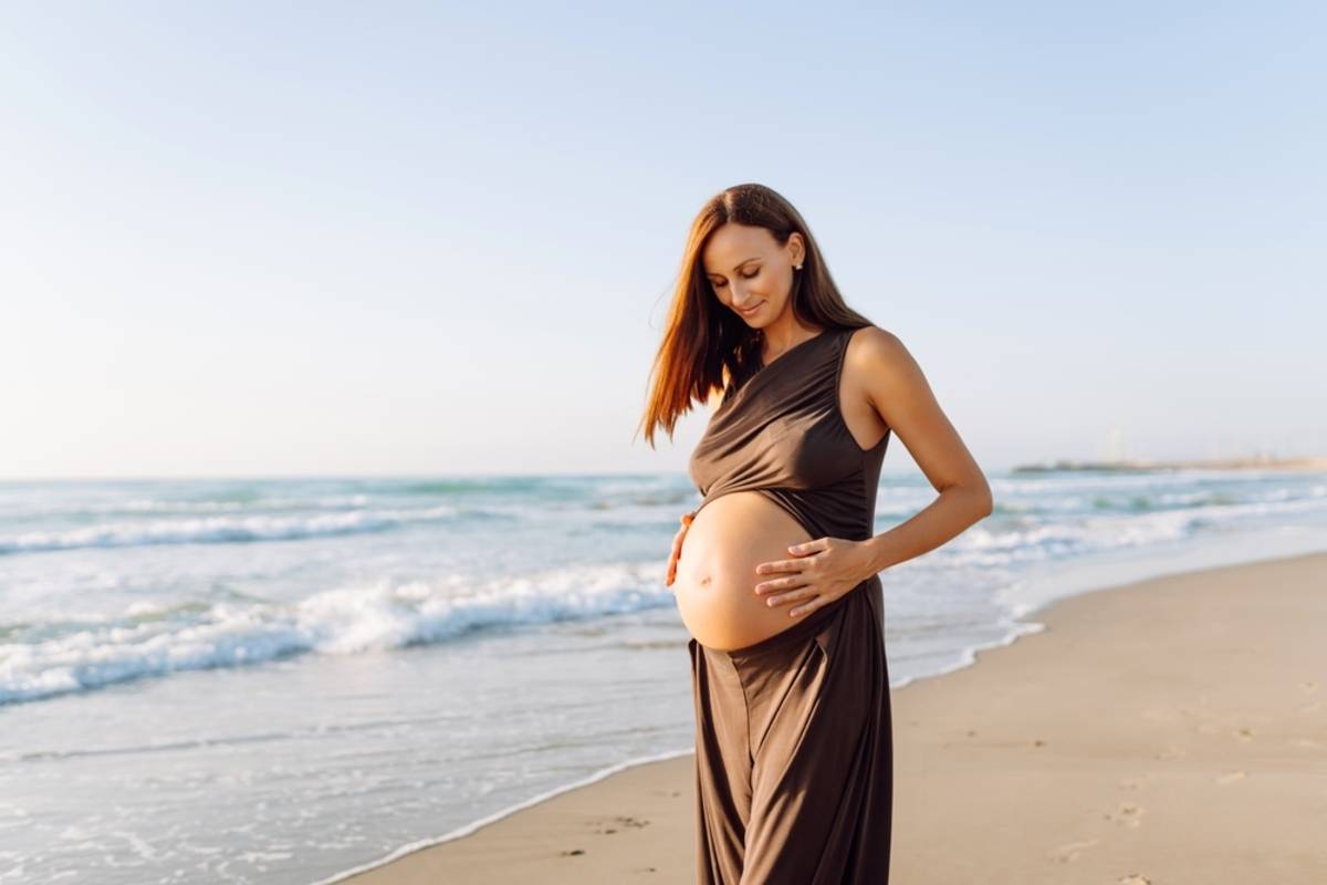 Pregnant woman in a brown dress by the ocean | Skylum Blog

