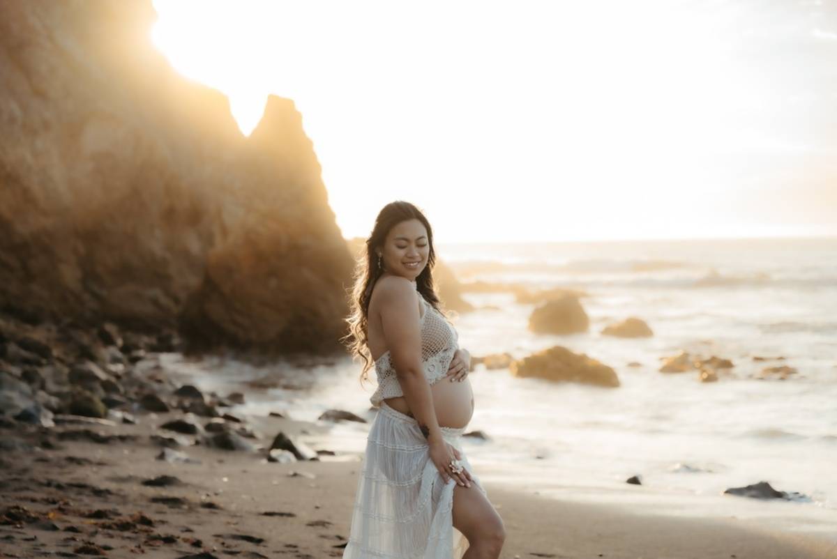 Pregnant woman walking on rocky beach at golden hour | Skylum Blog

