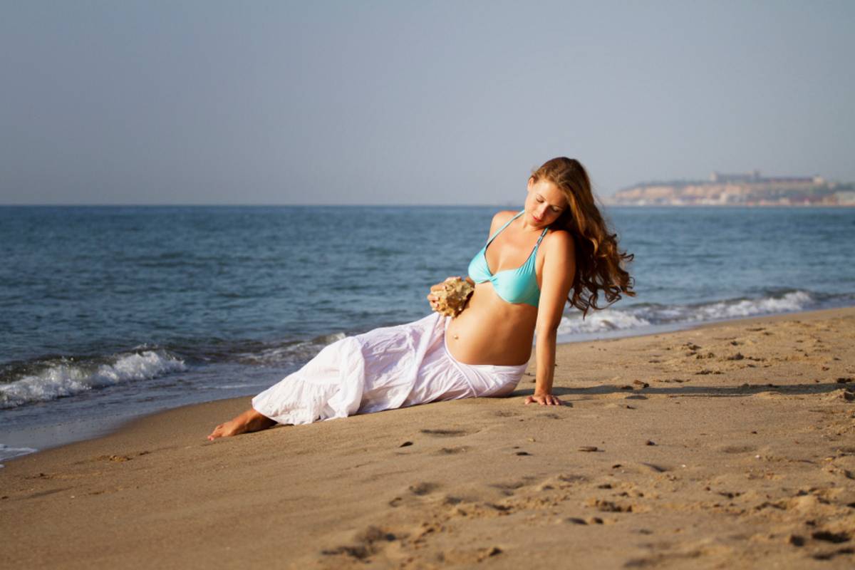 Pregnant woman lying on the beach by the sea | Skylum Blog

