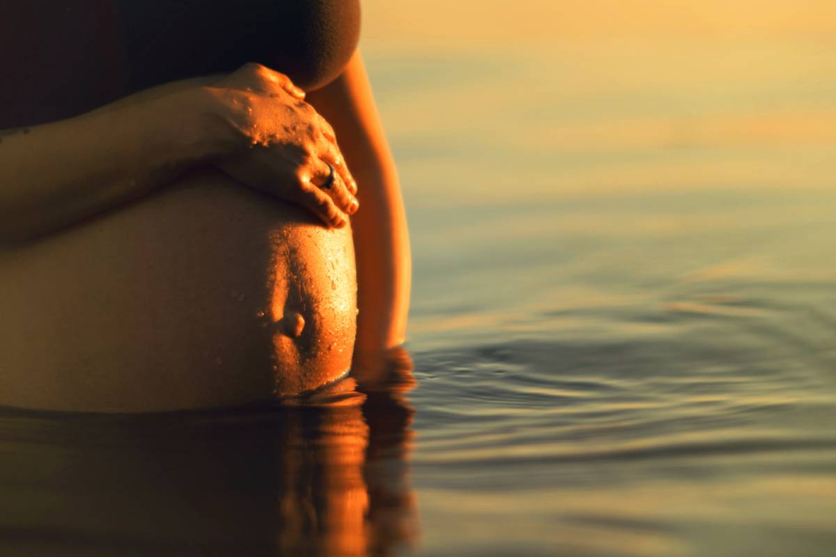 Close-up of pregnant belly by the water at sunset | Skylum Blog

