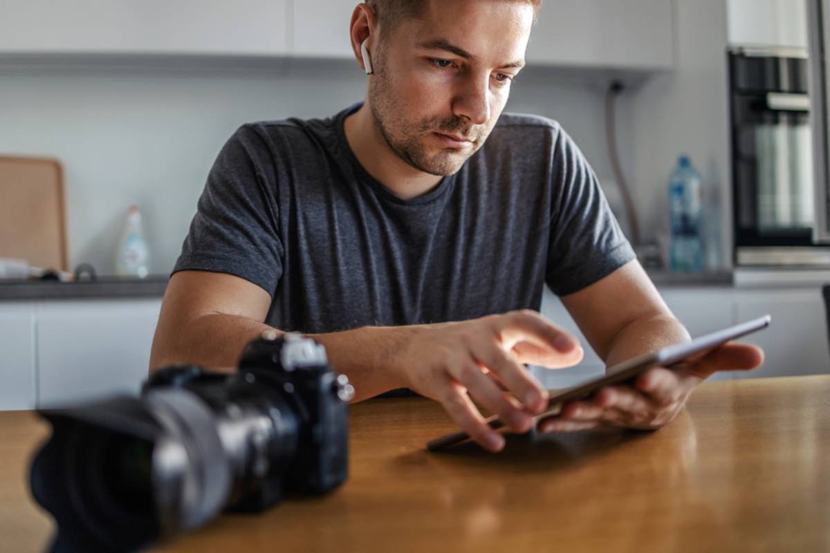 Una persona revisando fotos en una cámara, sentada en una mesa | Blog de Skylum