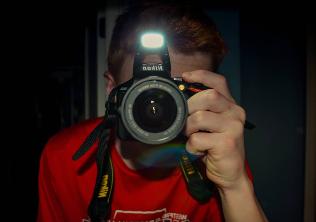 Photographer holding Nikon camera with flash | Skylum Blog

