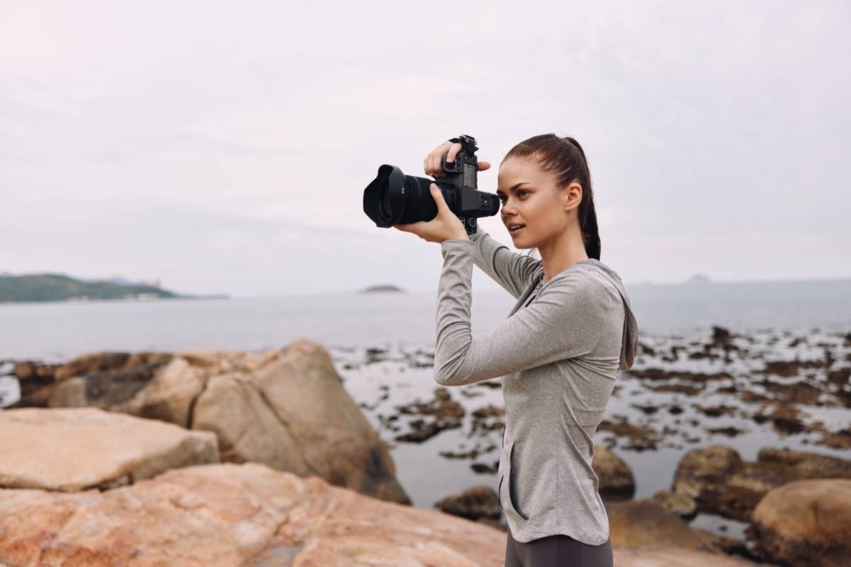 Woman taking photos on a rocky beach | Skylum Blog

