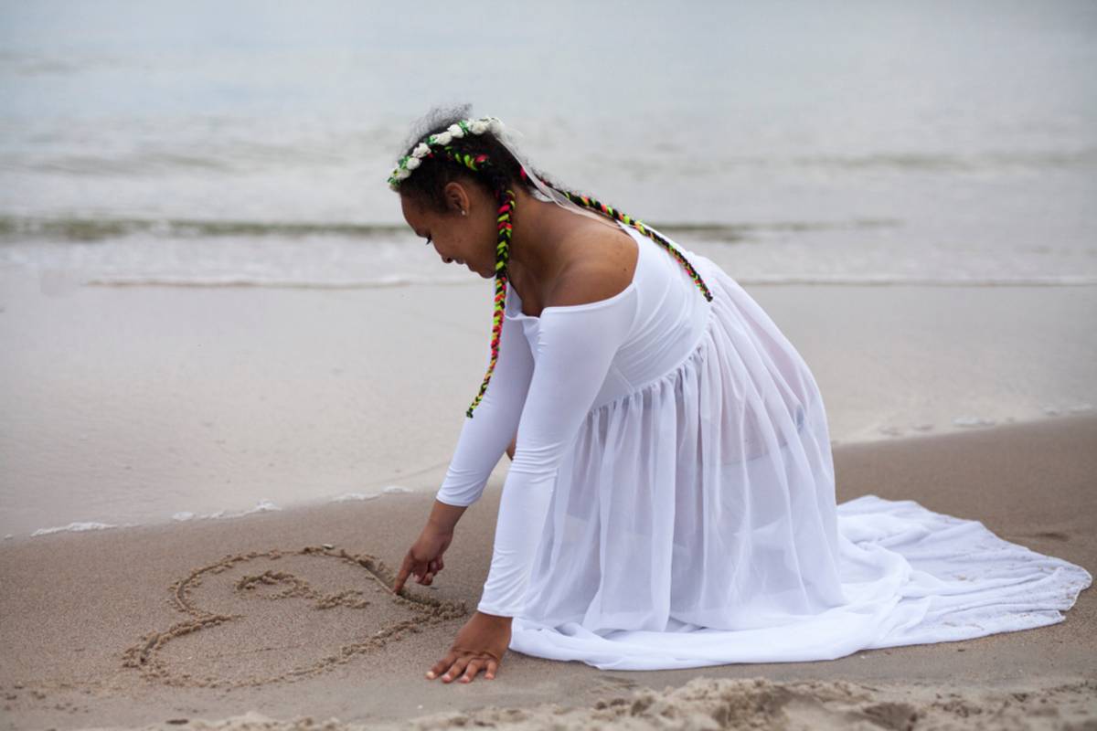Pregnant woman drawing a heart in wet sand | Skylum Blog

