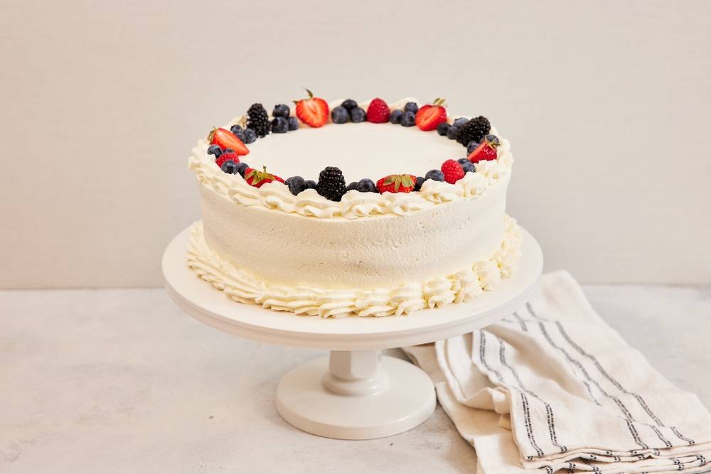 Berry white cake on a stand with simple backdrop | Skylum Blog


