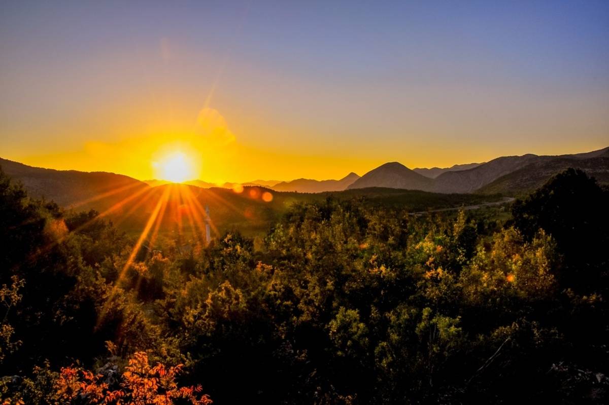 Bright golden sunburst rising over hills and greenery | Skylum Blog

