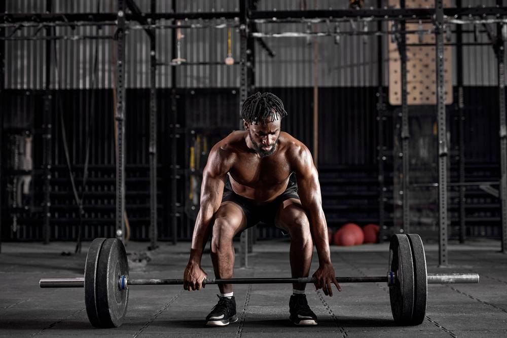 Young muscular african sweaty fit man with big muscles training 
