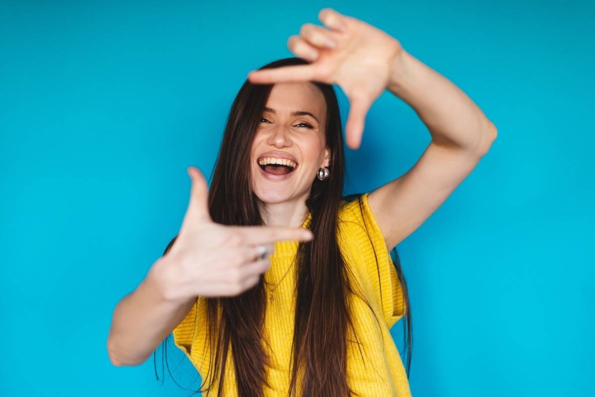 Smiling woman posing against a blue background | Skylum Blog

