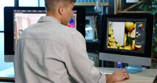 Editor at dual monitors with lemon photo and color wheel open beside a room interior edit
