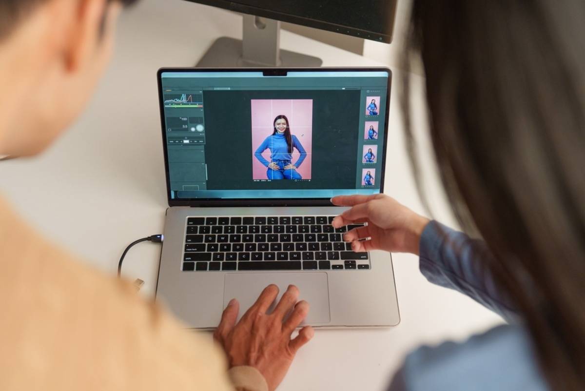 Two people reviewing a portrait in editing software on a laptop with a photo filmstrip