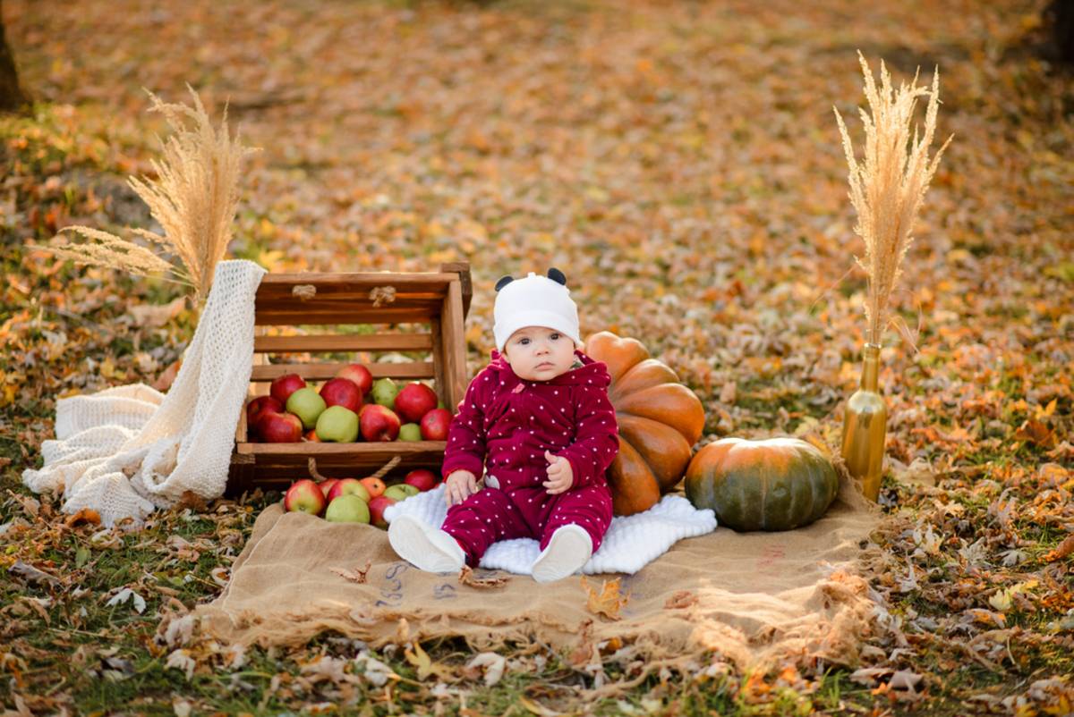 Baby sitting on a blanket outdoors in autumn park