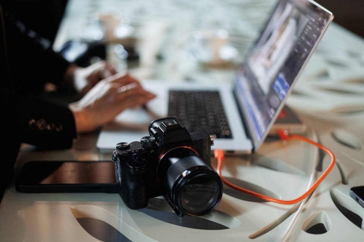 Mirrorless camera on a desk beside a laptop open to photo editing software