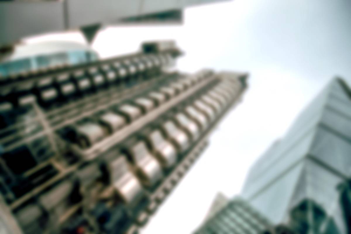 Blurred upward view of glass skyscrapers against a bright overcast sky
