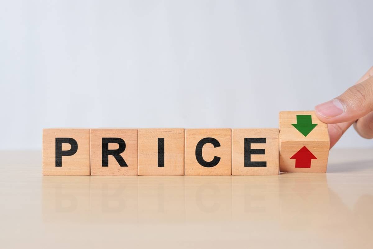 Wooden blocks spelling PRICE with a finger flipping a cube between up and down arrows